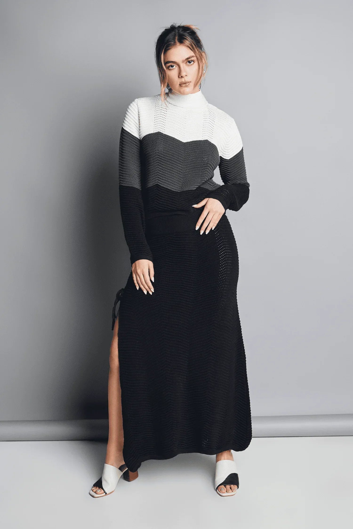 Mujer con vestido largo tejido de punto en tonos blanco, gris y negro, moda femenina elegante